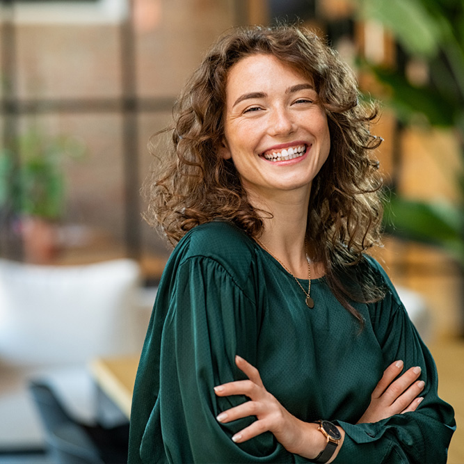 Woman with curly hair wearing a dark green blouse and a wristwatch - arlingtonagency.com