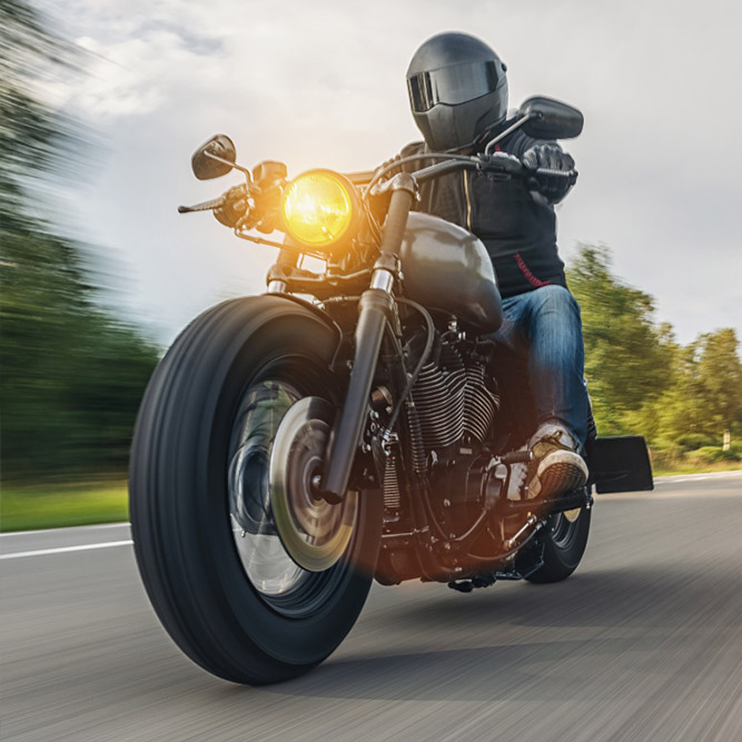 Person wearing black helmet and jacket riding a black motorcycle - arlingtonagency.com